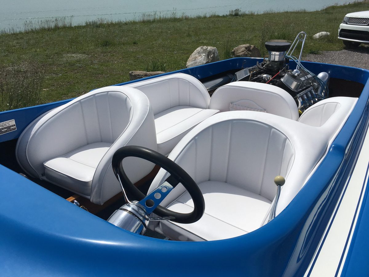The inside of a blue boat with white recovered seats and side panels.
