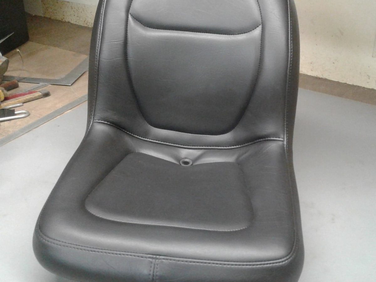 An equipment seat with a high back, recovered in heavy black vinyl.